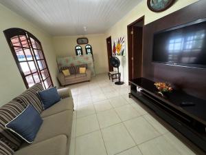 a living room with a couch and a flat screen tv at Caiçara's house in Praia de Araçatiba