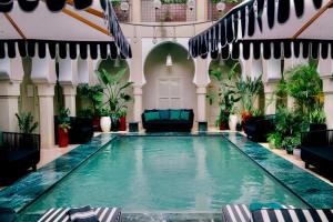 an indoor pool in a building with chairs and plants at Riad Nashira & Spa in Marrakesh