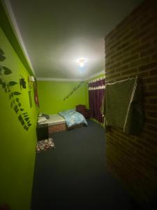 a green room with a bed and a brick wall at bekhal bhaktapur in Bhaktapur +1 photo