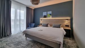 a bedroom with a large bed and a blue wall at Hotel Wolin in Międzyzdroje