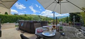 una mesa de madera con una sombrilla en el patio en Chez Mich'An Luberon, en Saignon