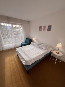 ein Schlafzimmer mit einem Bett, einem Stuhl und einem Fenster in der Unterkunft Ti Hou - T2 600 m plage - Lajarrige in La Baule-les-Pins