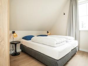 ein Schlafzimmer mit einem Bett mit weißen Laken und blauen Kissen in der Unterkunft Pretty Holiday Home in De Koog Texel with Garden in Westermient