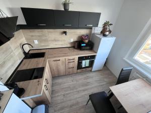 a small kitchen with wooden cabinets and a refrigerator at Apartmán Dona in Veľký Meder +1 photo