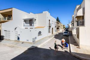 two women running down a street in a city at Hotel Calliope in San Vito lo Capo