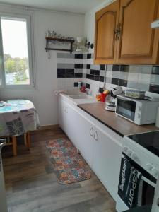 eine Küche mit einer Theke und einer Mikrowelle in der Unterkunft Spacieux appartement 4 pieces in Beauvais