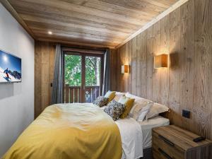 a bedroom with a large bed and a wooden wall at Appartement Neuf à Courchevel Le Praz - 8 Couchages, Proche Pistes, Terrasse Ensoleillée - FR-1-568-3 in Courchevel