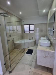 a bathroom with a shower and a tub and a sink at 8 Ladyfish Nook in Richards Bay
