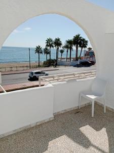 un arco con una silla blanca y la playa en El Flamenco, en Mojácar 3 fotos más
