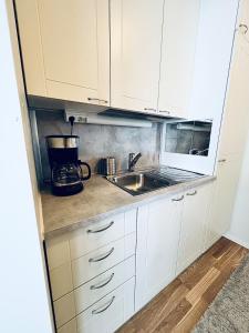 uma cozinha com armários brancos e uma pia em Spacious two-room apartment with sauna em Varkaus
