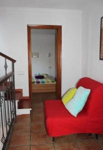 ein rotes Sofa in einem Zimmer mit einem Schlafzimmer in der Unterkunft Gemütliches Ferienhaus in Guaro mit Grill in Guaro + 6 Fotos