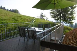 a table and chairs on a deck with an umbrella at Ferienwohnung Friesenhof Blank In Sulzberg in Sulzberg