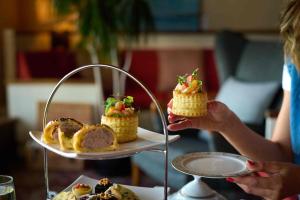 a woman holding up a plate of food on a table at Knoll House in Studland +53 photos