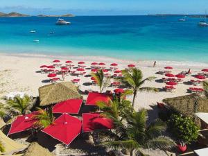 a beach with many red umbrellas and the ocean at Sand and Style, Baie Orientale in Saint Martin