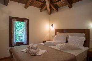 a bedroom with two towels on a bed with a window at To Mpalkoni in Chorefto