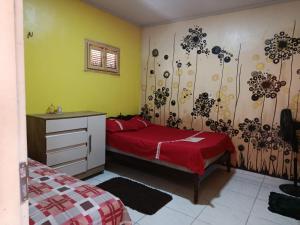 a bedroom with a red bed and a dresser in it at HospedagemCanoa in Aracati