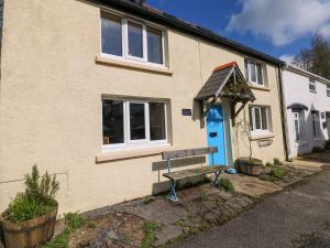 a house with a blue door and a bench in front at 1 Mill Farm Cottages in Narberth