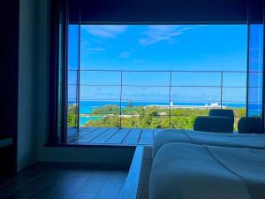 Un dormitorio con un gran ventanal con vista al mar. en Quan Sea Vista Retreat Japanese Room サウナ付き宿, en Onna