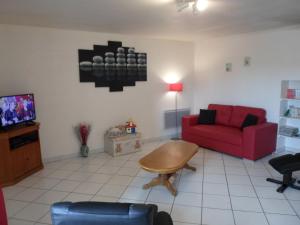 a living room with a red couch and a tv at Steinhaus In Ländlicher Umgebung Mit Pool in Brotte-lès-Ray