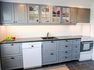 a kitchen with white and gray cabinets and a sink at Apartment Rorbuen by Interhome in Uggdal +15 photos