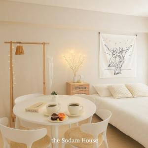een witte kamer met een bed en een tafel en stoelen bij the Sodam House in Seoul