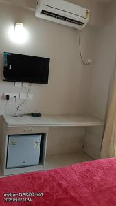 Zimmer mit einem Schreibtisch, einem TV und einem Ventilator. in der Unterkunft Shree ji sharnam in Vrindāvan
