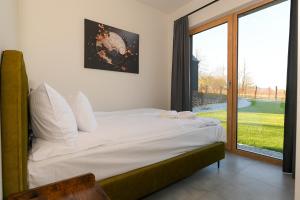 a bedroom with a bed and a large window at Górskie Kąty Resort Michałkowa in Michałkowa