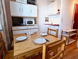 a small kitchen with a wooden table with plates on it at Studio cosy 3 places au pied des pistes, animaux acceptés - FR-1-340-124 in Chamrousse +14 photos