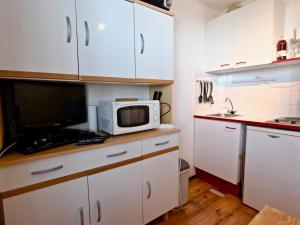 a kitchen with white cabinets and a microwave on a counter at Studio cosy 3 places au pied des pistes, animaux acceptés - FR-1-340-124 in Chamrousse