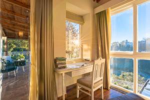 una oficina con escritorio y ventanas grandes en Casa De Bello, Nainital, Near Kainchi Dham, en Bhowāli