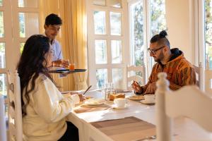 a group of people sitting around a table eating food at Casa De Bello, Nainital, Near Kainchi Dham in Bhowāli