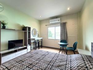a bedroom with a bed and a television and a table at Merit Courtyard Suvarnabhumi House in Lat Krabang