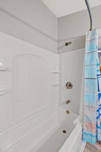a white bath tub with a shower curtain in a bathroom at Little blue house on the lake in Nancy