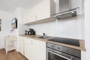 eine Küche mit weißen Schränken und einer Spüle in der Unterkunft Dorfring 36 Albatros in Stein