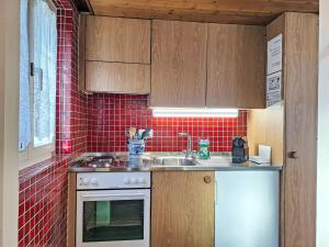 een keuken met een wastafel en rode tegels bij Apartment Chalet Auf dem Vogelstein-1 by Interhome in Grindelwald