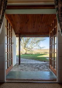 an open door to a patio with a tree in the background at Trumpetters Drift Private Wildlife Lodge in Grahamstown
