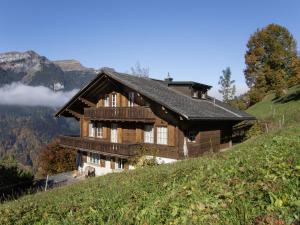a house on a hill with mountains in the background at Apartment Drei Tannen by Interhome in Wengen