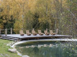 Benešov nad ČernouChalet Srub Kuří by Interhome的池塘上架着一座木桥，桥上摆放着椅子。