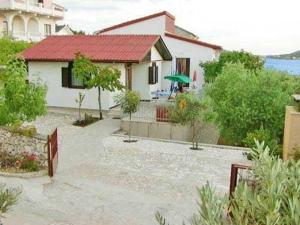 ein kleines weißes Haus mit einem roten Dach in der Unterkunft Ferienhaus mit Terrasse und Kinderpool an einer Bucht mit Meerblick in Rogoznica
