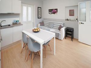 une cuisine et un salon avec une table et des chaises blanches dans l'établissement Apartment Grigio by Interhome, à Germignaga