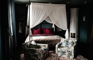 Un dormitorio con una cama con dosel y una silla. en Häckeberga Slott, en Genarp