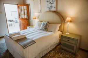 a bedroom with a large white bed and a table at The Townhouse in Graaff-Reinet