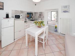une cuisine avec des armoires blanches et une table avec une plante dessus dans l'établissement Apartment White by Interhome, à Germignaga 25 autres photos