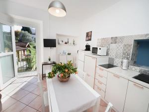 une cuisine avec des armoires blanches et une plante en pot sur une table dans l'établissement Apartment White by Interhome, à Germignaga