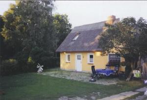 ein kleines gelbes Haus mit einer blauen Bank im Hof in der Unterkunft Freistehendes Ferienhaus in ruhiger Lage in Rubitz + 1 Foto