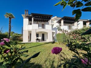 una gran casa blanca con un patio con flores en Villaggio Evanike, en Bibione