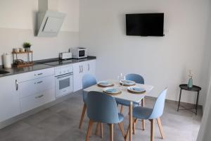 a kitchen with a white table and blue chairs at La Herrada Home in Los Montesinos