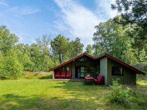 ein kleines Haus mit roten Stühlen auf einem Feld in der Unterkunft Holiday Home Elfrieda - 1-6km from the sea by Interhome in Læsø