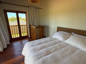 una camera da letto con un letto bianco e un balcone di Corumbau Bangalôs a Corumbau