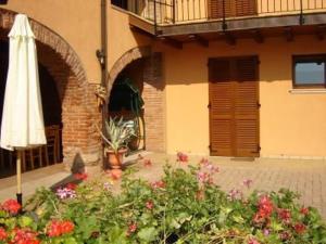 un parasol et des fleurs devant un bâtiment dans l'établissement Appartasmento Ficus, à bedizzol